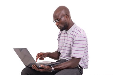 Genç adam optik gözlük takıyor sandalyede oturuyor ve dizüstü bilgisayarla çalışıyor..