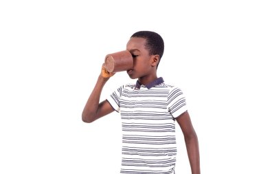 Beyaz arka planda duran tişörtlü genç bir bardaktan su içiyor..