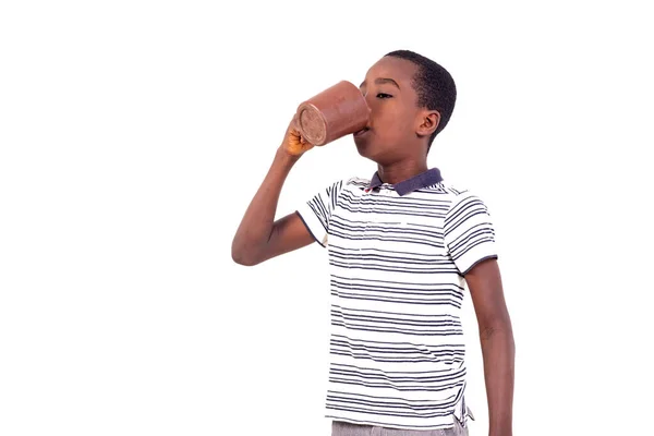 穿着T恤衫的小男孩站在白色的背景上 喝着杯子里的水 — 图库照片