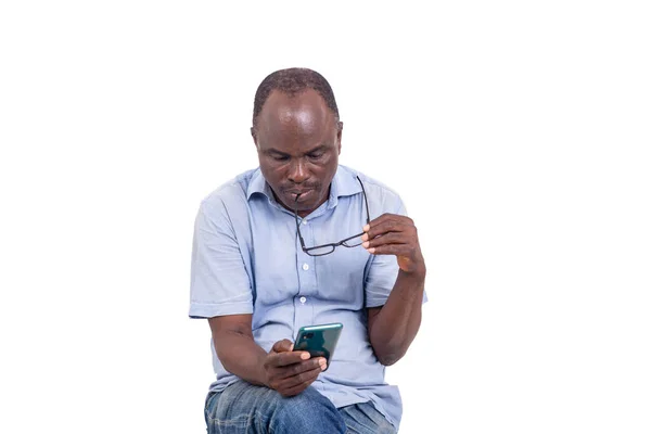 Zralý Muž Sedí Stoličce Nad Bílým Pozadím Dívá Zprávu Mobilu — Stock fotografie