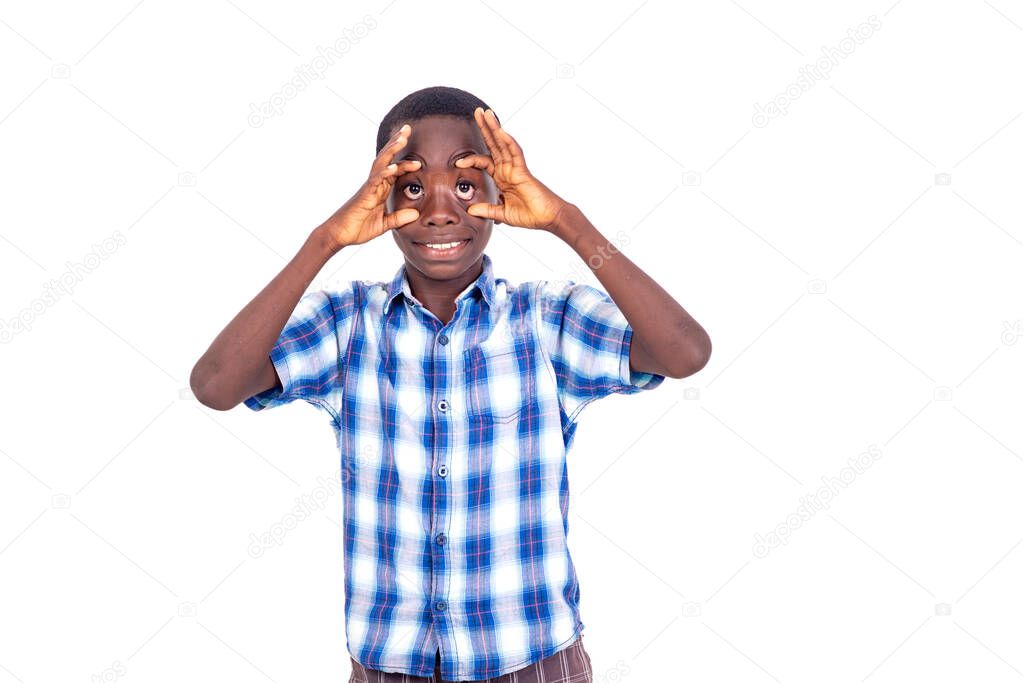 young boy in checkered shirt standing on white background making faces by opening his eyes using hands.