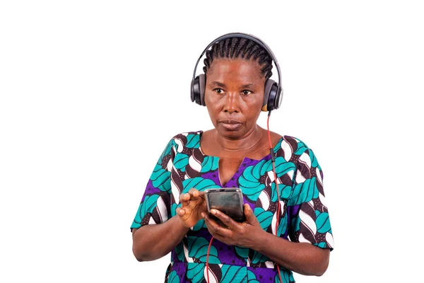携帯電話やイヤフォンを使って白い背景に立つアフリカ人女性 — ストック写真