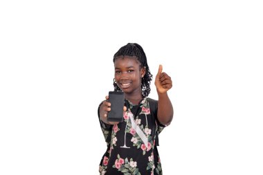 Beyaz arka planda duran örgülü genç kız gülümserken cep telefonunu gösteriyor.