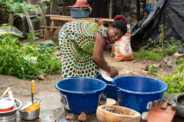 Abidjan, Fildişi Sahili - 25 Şubat 2022: Evin bahçesinde bulaşıkları yıkayan genç Afrikalı Amerikalı kadın