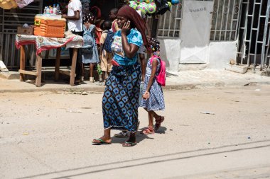 Abidjan, Fildişi Sahili - 14 Mart 2022 Okul çocuklarına okul yolunda eşlik eden genç bir kadın.