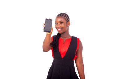 Kırmızı ve siyah kıyafetli güzel bir kız beyaz arka planda duruyor cep telefonunu sunuyor, gülüyor..