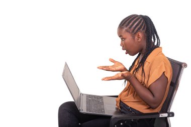 Pantolon giymiş genç bir bayan öğrenci evde oturmuş dizüstü bilgisayarla çalışıyor. Şaşırmış görünüyor..