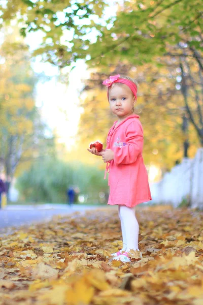 küçük kız sonbahar bir arka plan üzerinde bir elma yemek