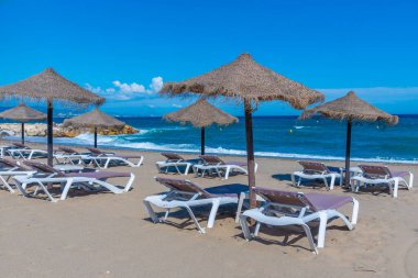 Marbella, İspanya 'daki Playa de Venüs' te güneşlik ve şemsiyeler.