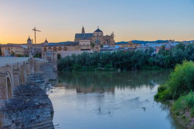 İspanya 'nın Cordoba şehrinde, ufukta La mezquita katedrali olan eski Roma köprüsünün günbatımı manzarası.