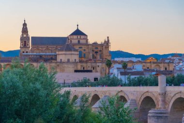 İspanya 'nın Cordoba şehrinde, ufukta La mezquita katedrali olan eski Roma köprüsünün günbatımı manzarası.