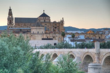 İspanya 'nın Cordoba şehrinde, ufukta La mezquita katedrali olan eski Roma köprüsünün günbatımı manzarası.