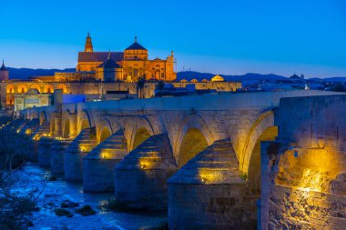 İspanya 'nın Cordoba şehrinde, ufukta La mezquita katedrali olan eski Roma köprüsünün günbatımı manzarası.