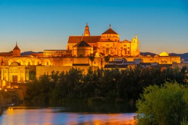 İspanya 'nın Cordoba şehrinde, ufukta La mezquita katedrali olan eski Roma köprüsünün günbatımı manzarası.