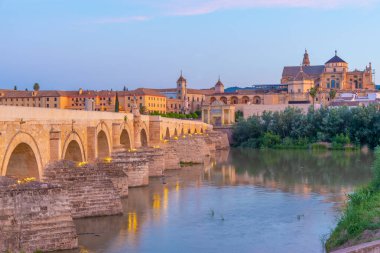 İspanya 'nın Cordoba şehrinde, ufukta La mezquita katedrali olan eski Roma köprüsünün gündoğumu manzarası.