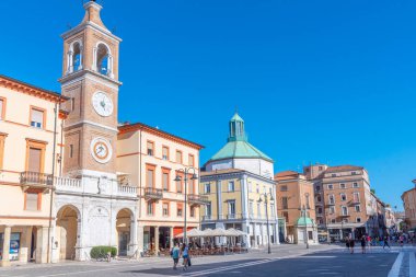 Rimini, İtalya, 2 Eylül 2021: İnsanlar İtalya 'nın Rimini şehrindeki Piazza Martiri' de bir saat kulesinin önünden geçiyorlar..