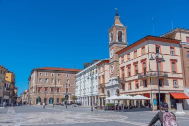 Rimini, İtalya, 2 Eylül 2021: İnsanlar İtalya 'nın Rimini şehrindeki Piazza Martiri' de bir saat kulesinin önünden geçiyorlar..