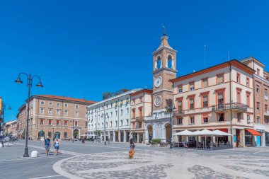 Rimini, İtalya, 2 Eylül 2021: İnsanlar İtalya 'nın Rimini şehrindeki Piazza Martiri' de bir saat kulesinin önünden geçiyorlar..