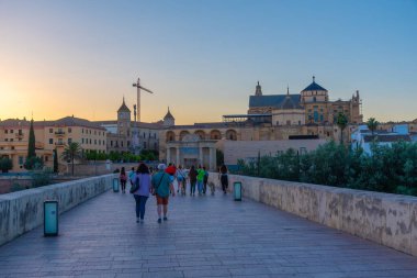 Cordoba, İspanya, 24 Mayıs 2021: İnsanlar İspanya 'nın Cordoba kentindeki Roma köprüsünden geçerek La mezquita katedraline doğru yürüyorlar..