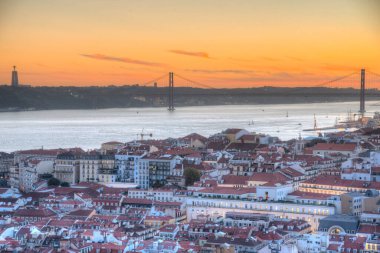 25 Nisan Köprüsü 'nün gün batımı manzarası ve Lizbon, Portekiz' deki Cristo Rei Ulusal Sığınağı.