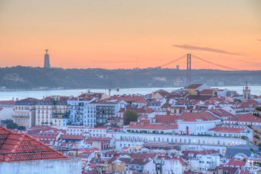 25 Nisan Köprüsü 'nün gün batımı manzarası ve Lizbon, Portekiz' deki Cristo Rei Ulusal Sığınağı.