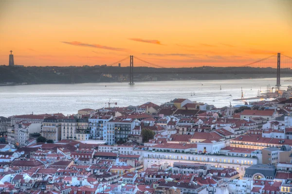 25 Nisan Köprüsü 'nün gün batımı manzarası ve Lizbon, Portekiz' deki Cristo Rei Ulusal Sığınağı.