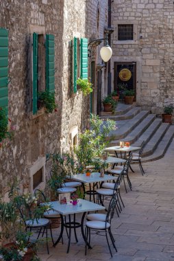 Hırvatistan 'ın eski Sibenik kentinde dar bir sokakta restoran masaları