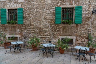 Hırvatistan 'ın eski Sibenik kentinde dar bir sokakta restoran masaları