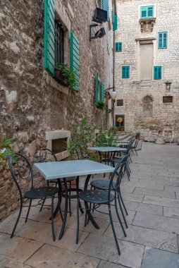 Hırvatistan 'ın eski Sibenik kentinde dar bir sokakta restoran masaları