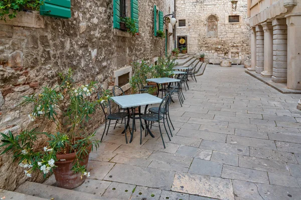 Hırvatistan 'ın eski Sibenik kentinde dar bir sokakta restoran masaları