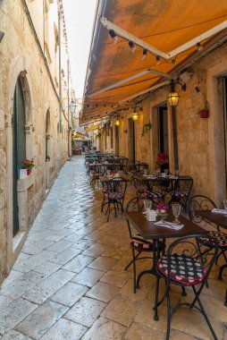 Hırvatistan 'ın eski Dubrovnik kentinde dar bir sokakta restoran masaları