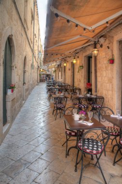 Hırvatistan 'ın eski Dubrovnik kentinde dar bir sokakta restoran masaları