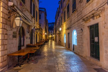 Hırvatistan 'ın eski Dubrovnik kentinde dar bir sokakta restoran masalarının gündoğumu manzarası