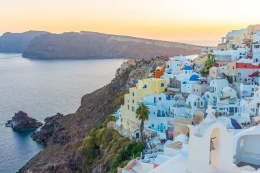 Yunanistan 'ın Santorini kentindeki Oia kasabasının günbatımı ve mavi kupa manzarası