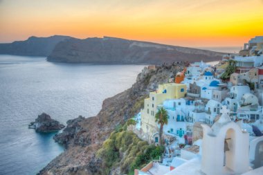 Yunanistan 'ın Santorini kentindeki Oia kasabasının günbatımı ve mavi kupa manzarası