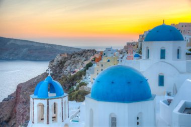 Yunanistan 'ın Santorini kentindeki Oia kasabasının günbatımı ve mavi kupa manzarası