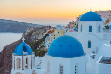 Yunanistan 'ın Santorini kentindeki Oia kasabasının günbatımı ve mavi kupa manzarası