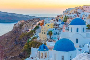 Yunanistan 'ın Santorini kentindeki Oia kasabasının günbatımı ve mavi kupa manzarası