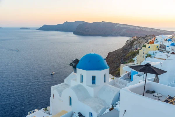 Yunanistan 'ın Santorini kentindeki Oia kasabasının günbatımı ve mavi kupa manzarası