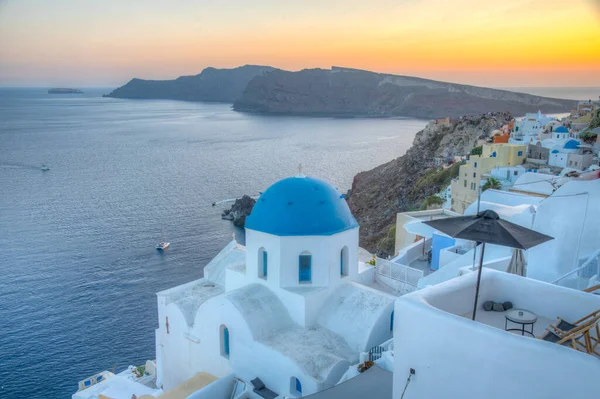 Yunanistan 'ın Santorini kentindeki Oia kasabasının günbatımı ve mavi kupa manzarası