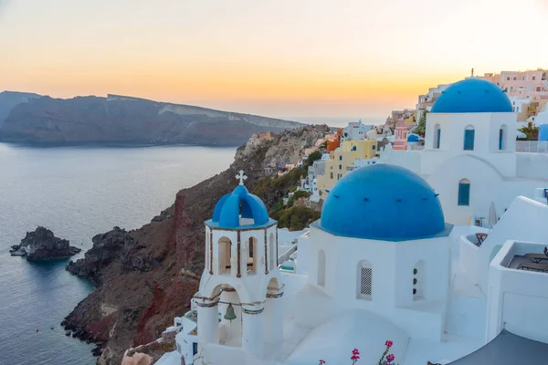 Yunanistan 'ın Santorini kentindeki Oia kasabasının günbatımı ve mavi kupa manzarası