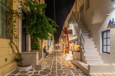 Mykonos, Yunanistan, 26 Eylül 2020: Yunanistan 'ın eski Mykonos kentindeki dar bir sokaktaki turist dükkanlarının gece manzarası
