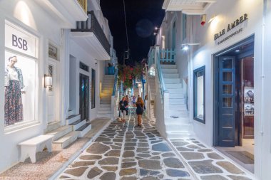 Mykonos, Yunanistan, 26 Eylül 2020: Yunanistan 'ın eski Mykonos kentindeki dar bir sokaktaki turist dükkanlarının gece manzarası