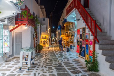 Mykonos, Yunanistan, 26 Eylül 2020: Yunanistan 'ın eski Mykonos kentindeki dar bir sokaktaki turist dükkanlarının gece manzarası