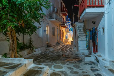 Mykonos, Yunanistan, 26 Eylül 2020: Yunanistan 'ın eski Mykonos kentindeki dar bir sokaktaki turist dükkanlarının gece manzarası