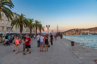 Trogir, Hırvatistan, 22 Temmuz 2020: Hırvatistan 'ın Trogir kentinde insanlar gün batımında deniz kenarında geziniyorlar