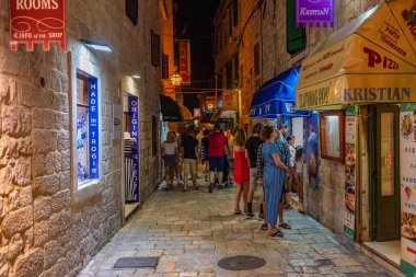 Trogir, Hırvatistan, 22 Temmuz 2020: İnsanlar, Hırvatistan 'ın Trogir kentindeki eski dar bir sokakta gece boyunca dolaştılar