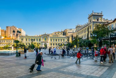 ATHENS, GREECE, 10 ARALIK 2015: İnsanlar Atina belediye binasının önündeki Kotzia meydanında güvercinleri besliyor.
