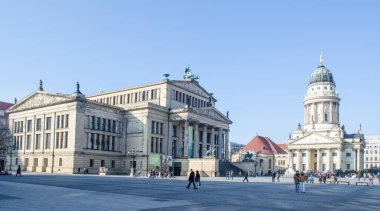 BERLIN, GERMANY, MARCH 12, 2015: people are walking through famous gendarmenmarkt in berlin famous for buildings of deustcher dom, french friedrichstadt church and konzerthaus berlin.
