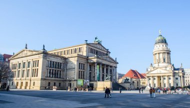 BERLIN, GERMANY, MARCH 12, 2015: people are walking through famous gendarmenmarkt in berlin famous for buildings of deustcher dom, french friedrichstadt church and konzerthaus berlin.